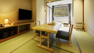 Tatamizimmer mit Tisch, Stühlen und Sitzbereich am Fenster