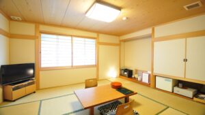 Chambre en tatami avec table basse, chaises et télévision