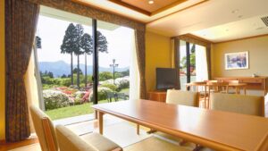 Zimmer mit Tisch, Stühlen und großen Fenstern zum Garten