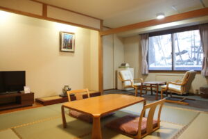 低いテーブルと窓際の椅子がある畳の部屋