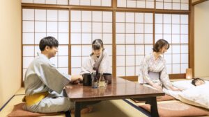 Menschen in Yukata um einen niedrigen Tisch und Futon