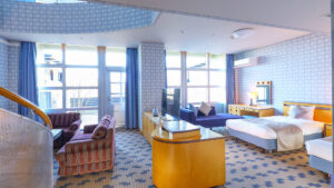 Gästezimmer mit Betten, Sofasitzbereich und großen Fenstern