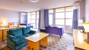 Gästezimmer mit Sofas, Tisch und großen Fenstern