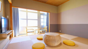 Tatamizimmer mit niedrigem Tisch, Sitzkissen und Stühlen am Fenster