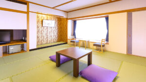 Habitación de tatami con mesa baja, cojines de suelo y sillas junto a la ventana