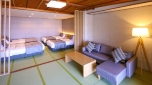 Habitación de tatami con sofá, mesa y dos camas individuales