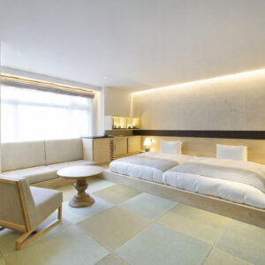 Zwei Einzelbetten neben Sofa und Tisch im Tatami-Zimmer