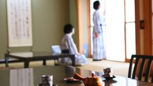 Chambre en tatami avec table basse, théière et clients assis