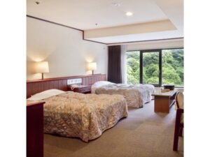 Letti singoli accanto a una finestra con vista sulla foresta