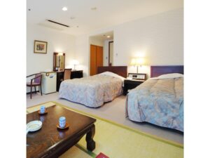 Letti singoli in una camera con area salotto in tatami