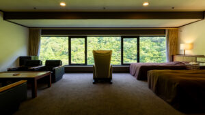 Letti singoli in camera con ampia finestra affacciata sulla foresta