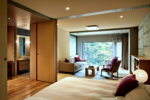 Gästezimmer mit Bett, Sofa, Stühlen und Fensterblick