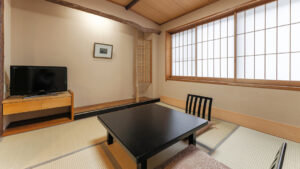 Chambre en tatami avec table basse, chaises et télévision