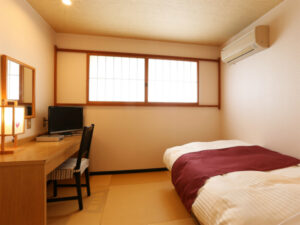 Cama individual junto al escritorio y la ventana en la habitación