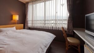 Letto matrimoniale accanto alla finestra e a una scrivania con sedia