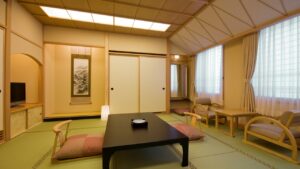 Camera con tatami, tavolino basso e sedie accanto alla finestra