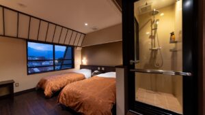 Letti singoli accanto a una doccia con pareti in vetro