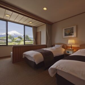 Letti singoli accanto a una grande finestra con vista sulle montagne