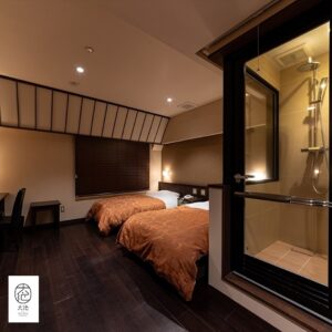 Camera con due letti singoli accanto a una doccia in vetro