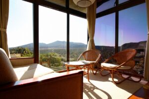 Rattan chairs by large windows overlooking mountain scenery