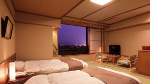 Tatami room with two beds, chairs, and window view