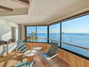 大きな海側の窓のそばにある客室内の椅子とテーブル