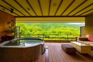 Rotenbad neben einem Sitzbereich mit Blick auf grüne Hügel