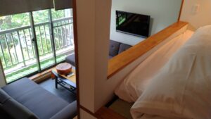 Bett neben einem kleinen Sitzbereich und Balkontürfenster
