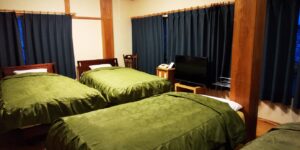 Gästezimmer mit drei Betten und grünen Tagesdecken