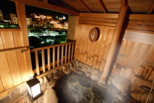 Bagno in pietra all'aperto su un balcone in legno di notte
