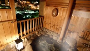Bagno privato all'aperto in legno con vista notturna sulla città