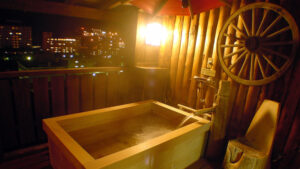 Bagno all'aperto privato in legno su un balcone di notte