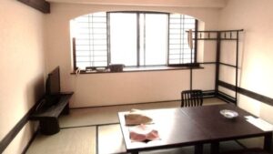 Camera in tatami con tavolo basso, sedie e televisore