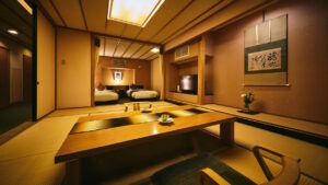 Chambre en tatami avec table basse et lits en arrière-plan