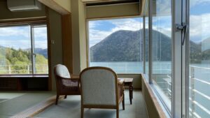 Blick auf See und Berge aus den Zimmerfenstern mit Stühlen