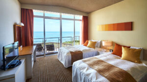 바다가 보이는 발코니를 향한 게스트룸의 트윈 베드