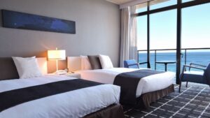 바다 전망 발코니를 향한 게스트룸의 트윈 침대