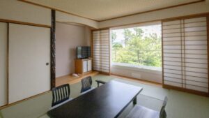 Camera in tatami con tavolo basso, sedie e finestra