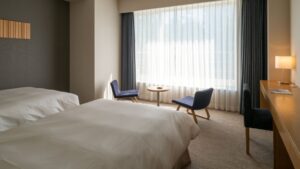 Letti singoli accanto a una zona salotto vicino alla finestra e a una scrivania