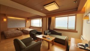 Chambre avec lits jumeaux, coin salon avec canapé et fenêtres