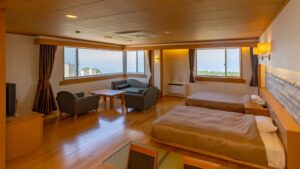 Chambre avec lits jumeaux, coin salon avec canapé et fenêtres