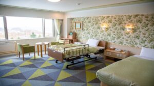 Lits de style hospitalier dans une chambre avec grande fenêtre