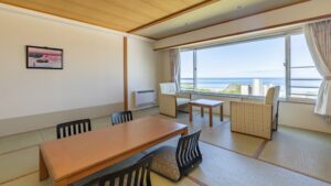 Chambre en tatami avec table basse, chaises et fenêtre sur l’océan