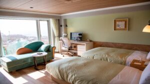 Lits jumeaux à côté d’une banquette près de la fenêtre et d’un bureau