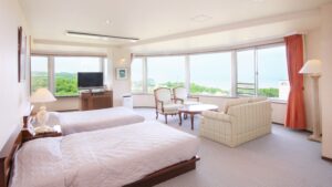 Lits jumeaux dans une chambre lumineuse avec canapé et fenêtres