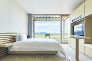 Chambre avec grand lit et fenêtre donnant sur les champs