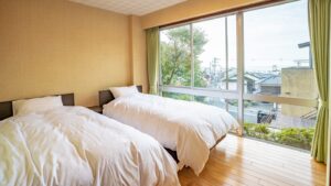 Two twin beds beside a large window.