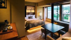 ベッド、ローテーブル、窓のある畳敷きの客室