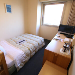Single bed beside desk and window