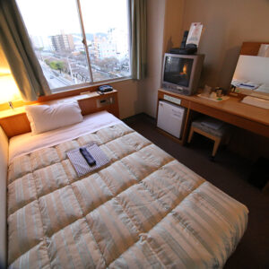 Single bed beside window, desk, and television